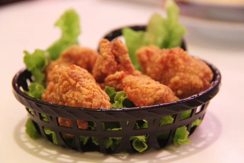 Fried chicken served in a basket with salad leaves