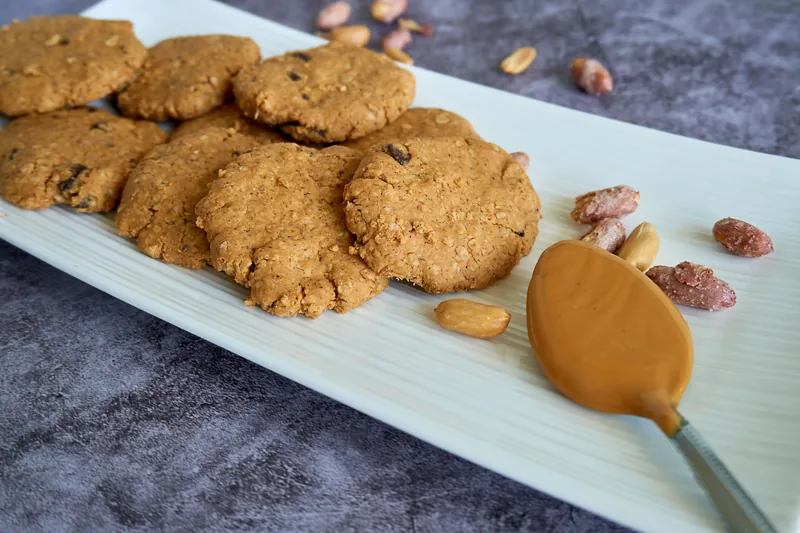 Peanut butter cookies on a tray with a spoonful of peanut butter