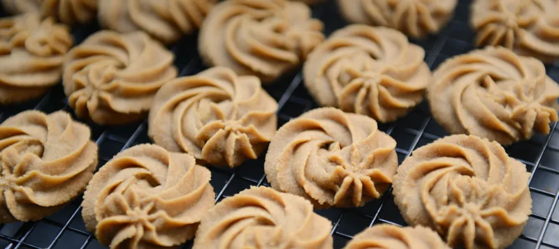 Piped peanut butter cookies cooling on a rack