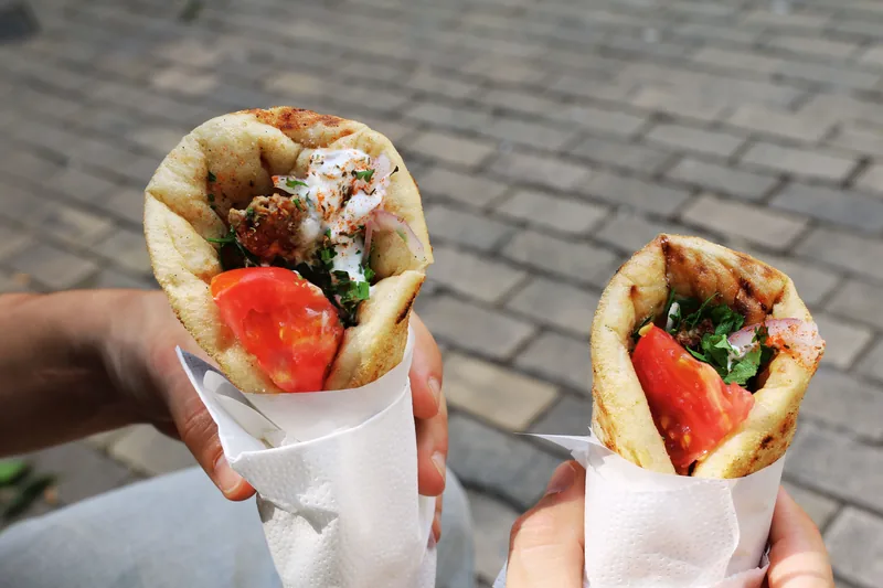 Two chicken gyros wrapped in paper with tomato and herbs
