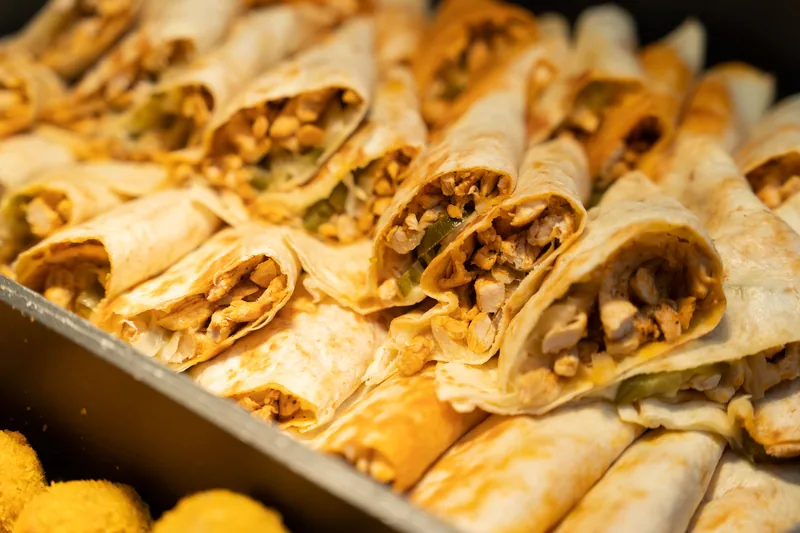 A tray of rolled filled tortillas packed side by side, ends open