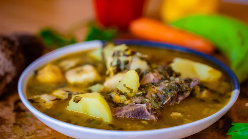 A bowl of beef and potato soup with carrots