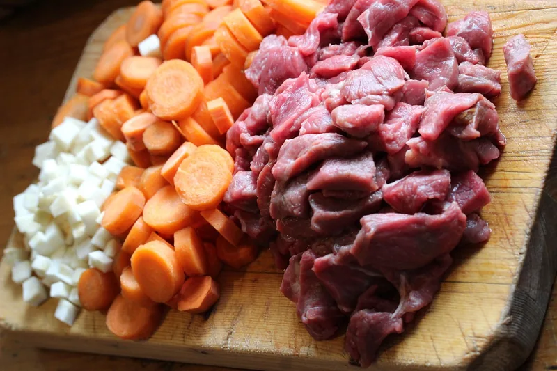 Cubed beef, diced carrots and onion on a cutting board