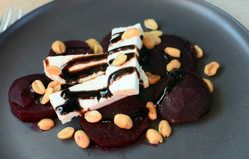Beet slices with rounds of goat cheese, nuts and balsamic