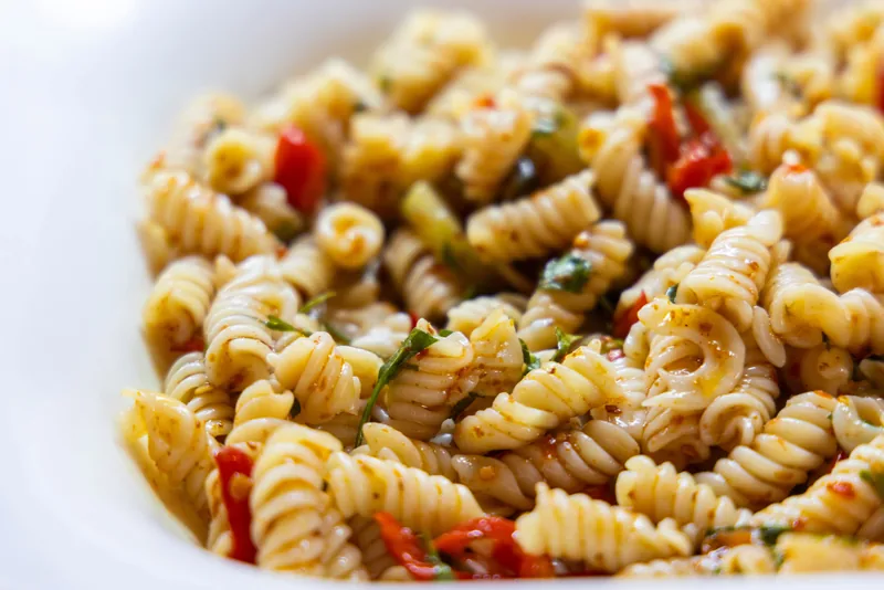 A close-up of pasta salad with peppers and herbs