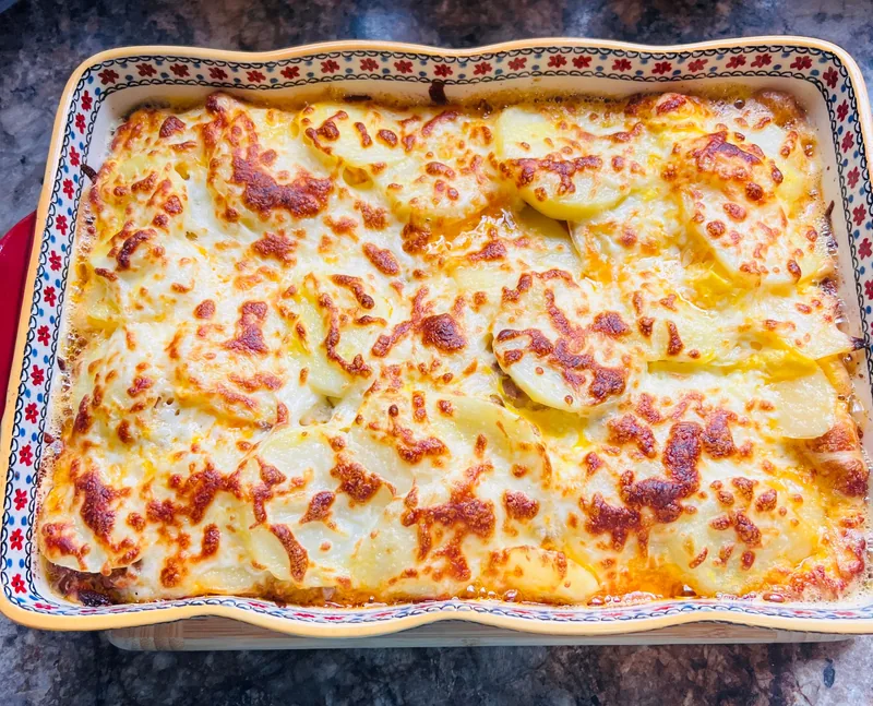 A baking dish of scalloped potatoes with a browned, bubbling top