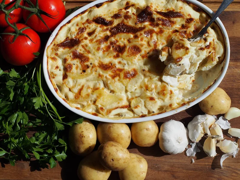 A potato gratin with tomatoes, parsley and whole potatoes around it