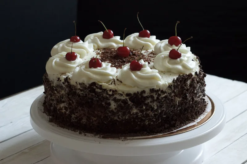 A Black Forest cake with whipped cream rosettes, cherries and chocolate shavings