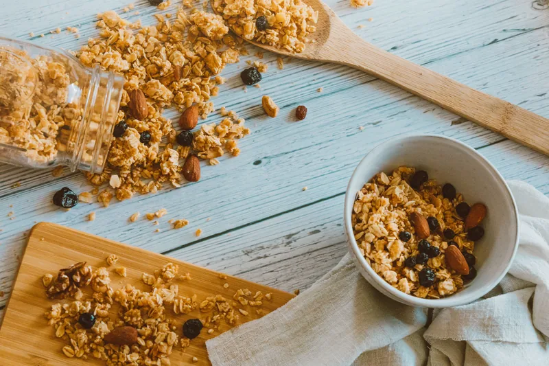 Toasted oat clusters spilling from a jar onto a board