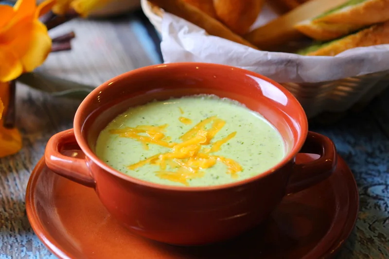 A bowl of broccoli soup topped with shredded cheddar