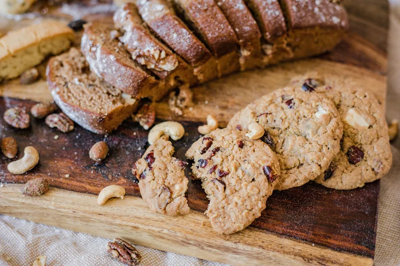 Soft nut-studded cookies and sliced quick bread on a wooden board