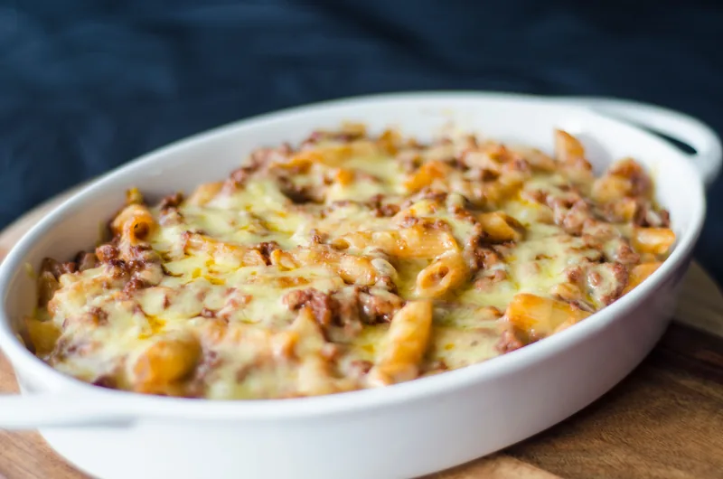 A baking dish of pasta under a browned layer of melted cheese