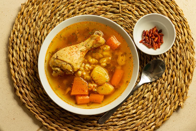 A bowl of chicken stew with carrots and potatoes