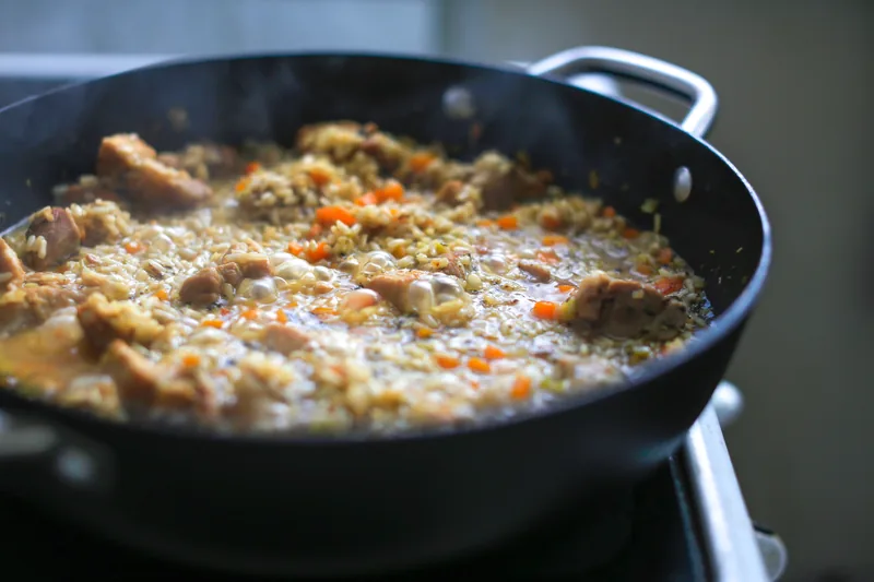 Chicken and rice simmering in a deep skillet