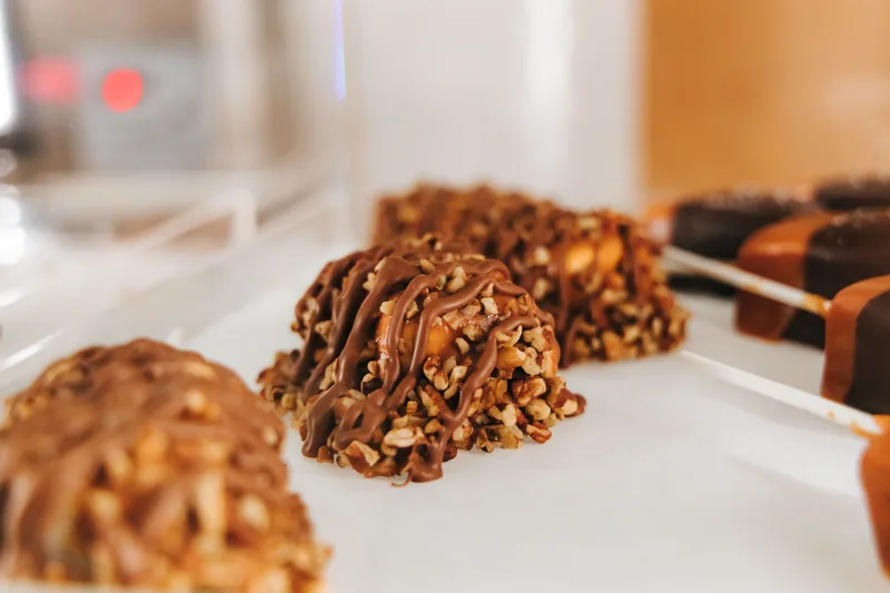 Chocolate-coated nut clusters lined up on a tray, pecans visible through the coating