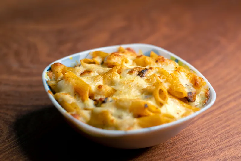 Baked pasta with melted cheese in a white dish