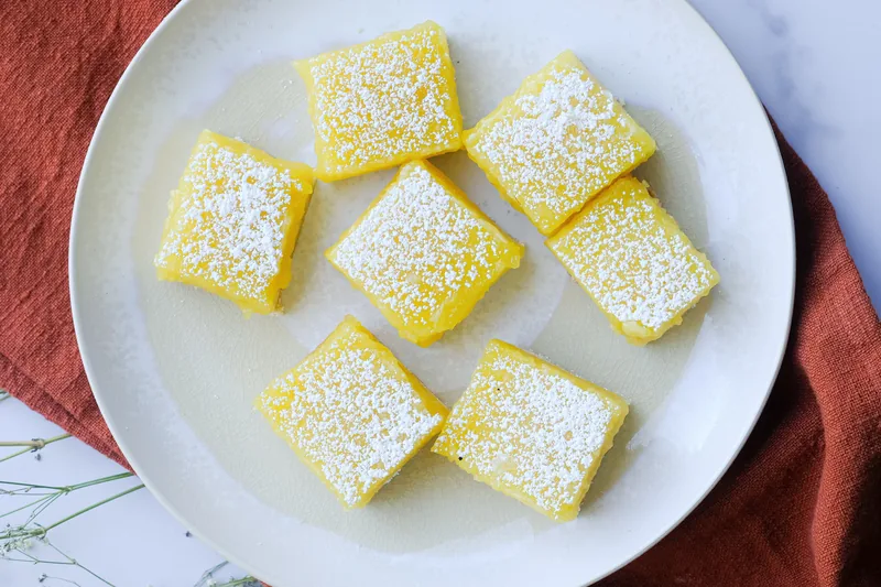 Lemon bars dusted with powdered sugar on a white plate