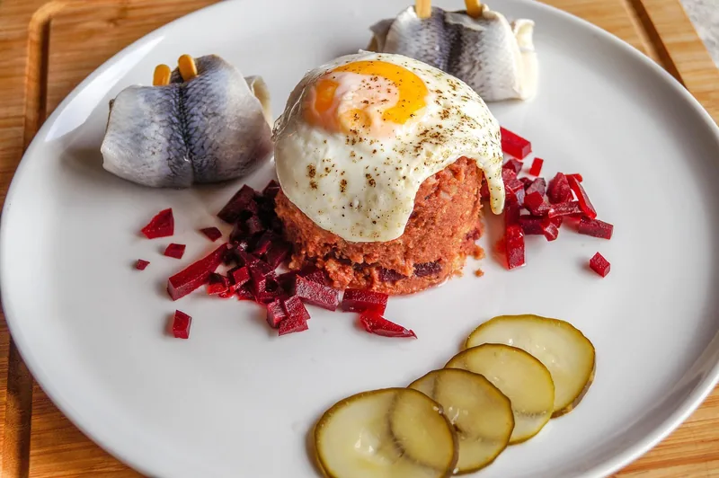 Corned beef hash with a fried egg and sliced pickles