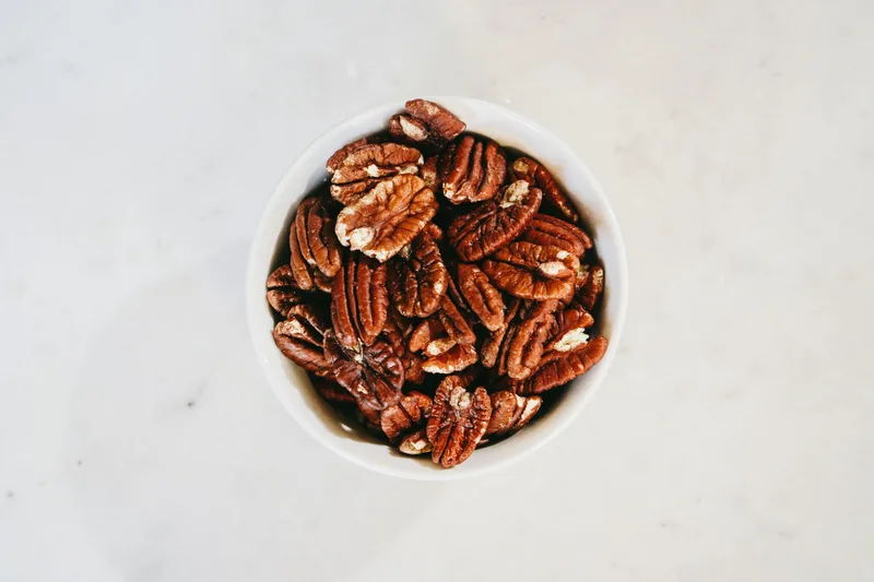 Shelled pecan halves in a small white bowl