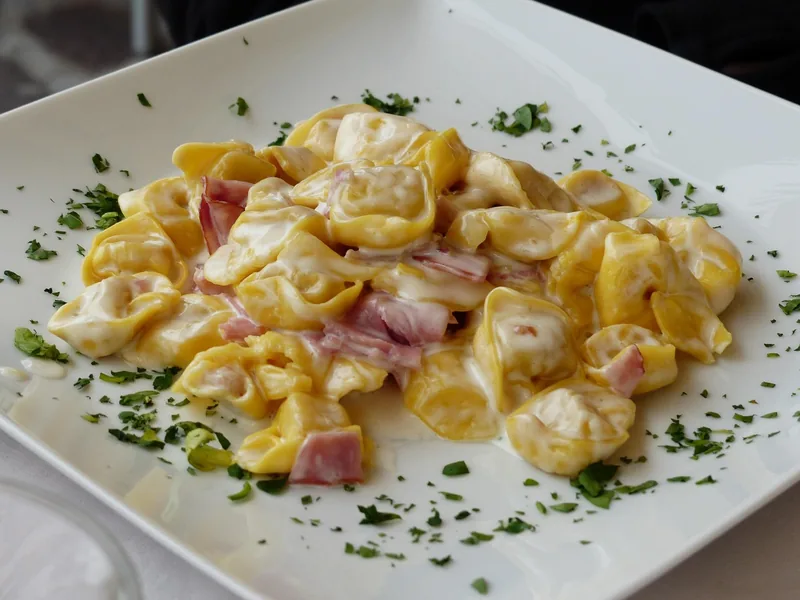 Tortellini in a creamy sauce with ham and parsley