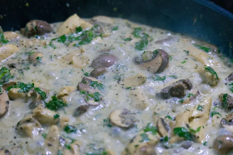 Creamy mushroom sauce simmering in a pan with parsley