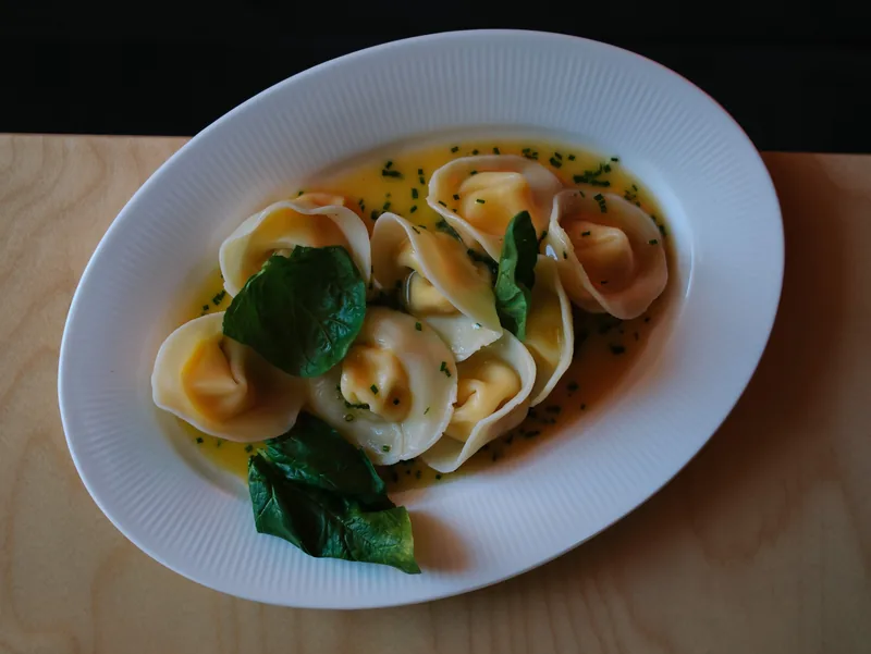 Tortellini in broth with spinach leaves