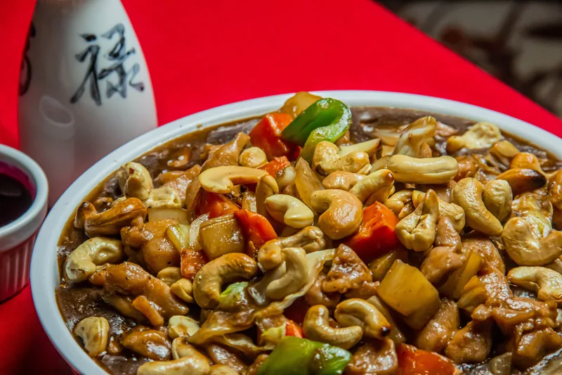 A bowl of cashew chicken with peppers in a glossy brown sauce