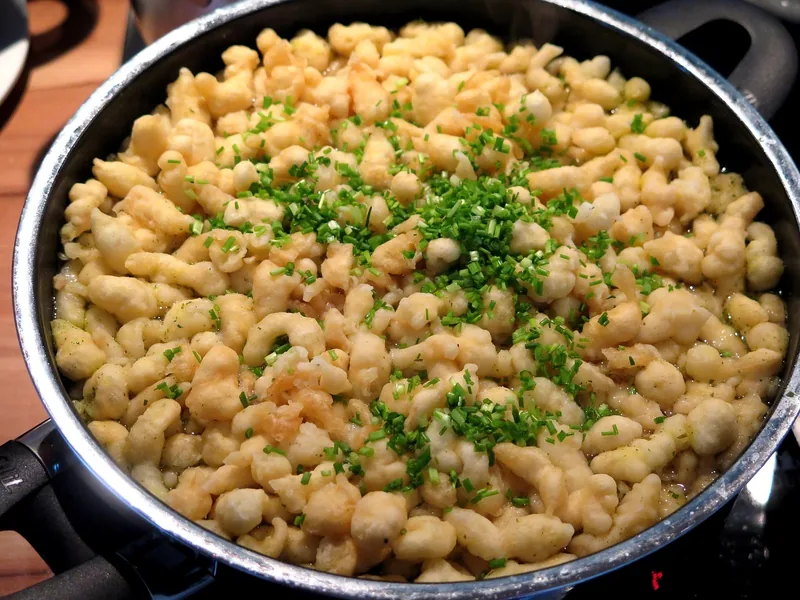 A pan of gnocchi in a creamy broth scattered with chives