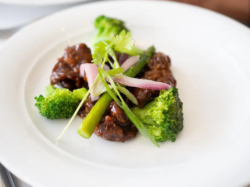 Beef and broccoli plated with a glossy sauce