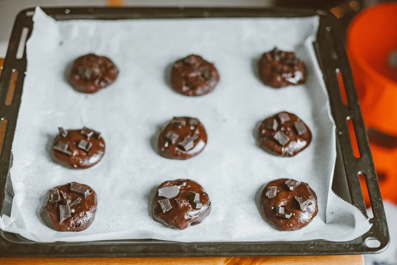 A tray of freshly baked chocolate cookies on parchment