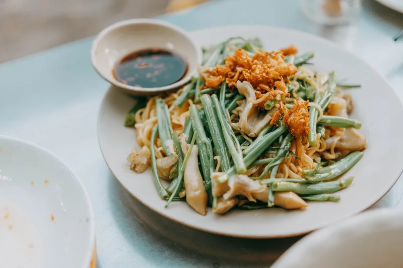 Green beans topped with crispy fried onions on a white plate
