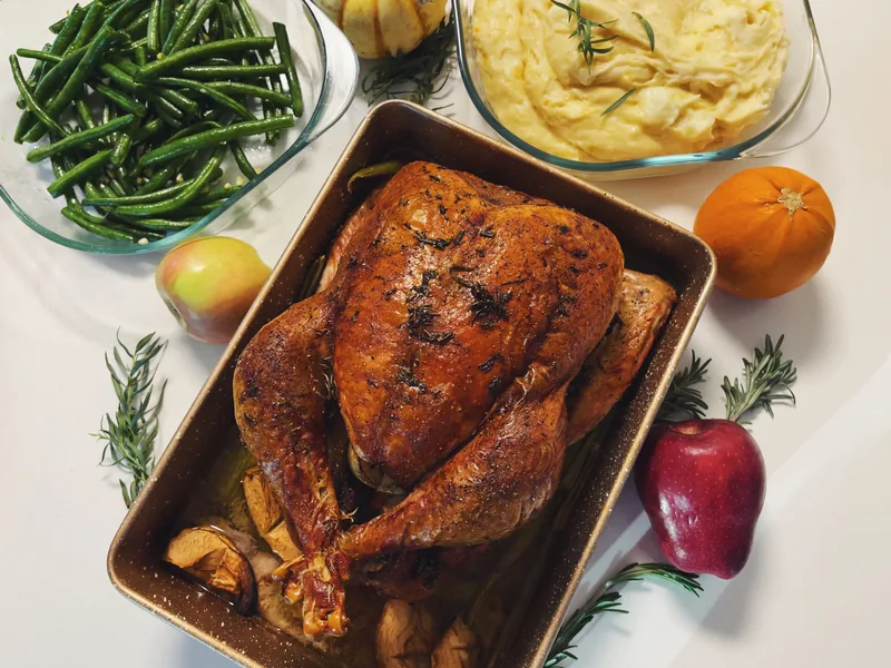 A roast turkey on a holiday table with green beans and mashed potatoes