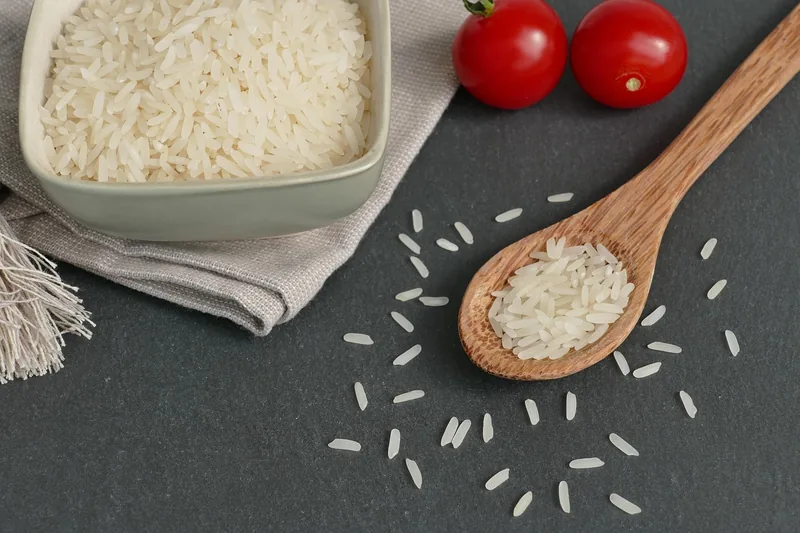 Uncooked long-grain rice with a wooden spoon