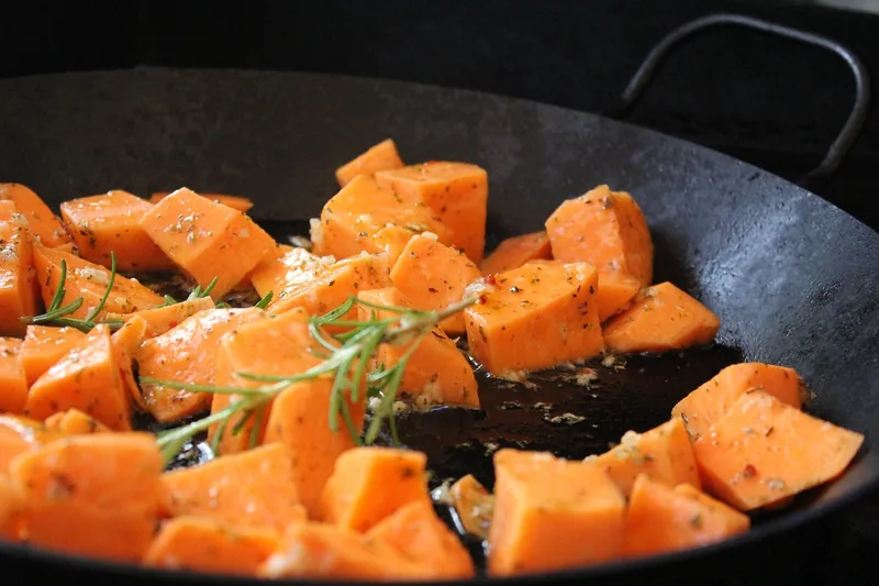 Roasted sweet potato chunks with rosemary in a black pan