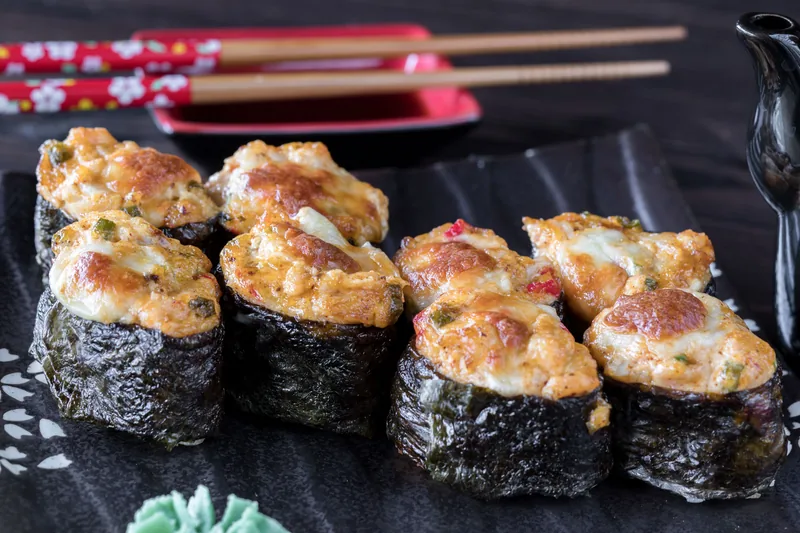 Sushi pieces baked under a browned creamy seafood topping