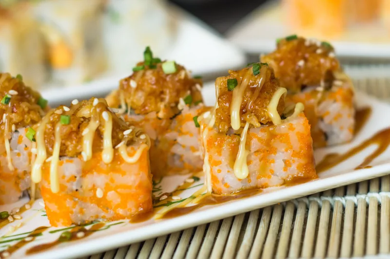 Sushi rolls topped with spicy mayo and sauce