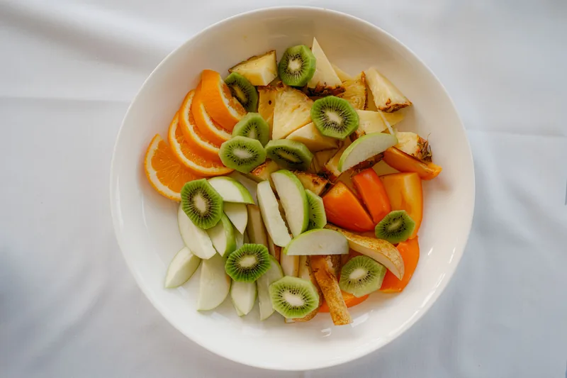A bowl of sliced kiwi, apple, pear and orange