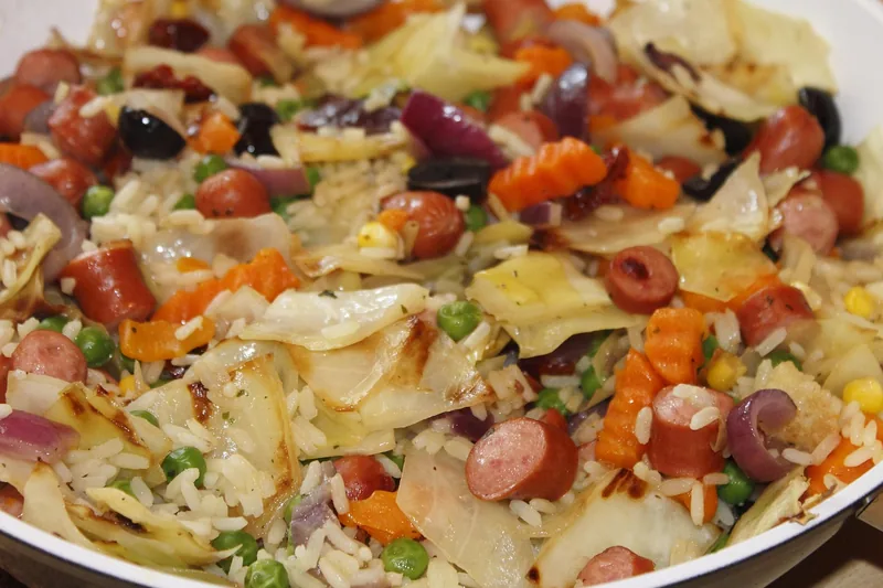 A skillet of sliced sausage with cabbage, peppers and vegetables
