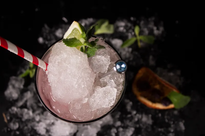 A glass of crushed-ice lemon slush with a striped straw