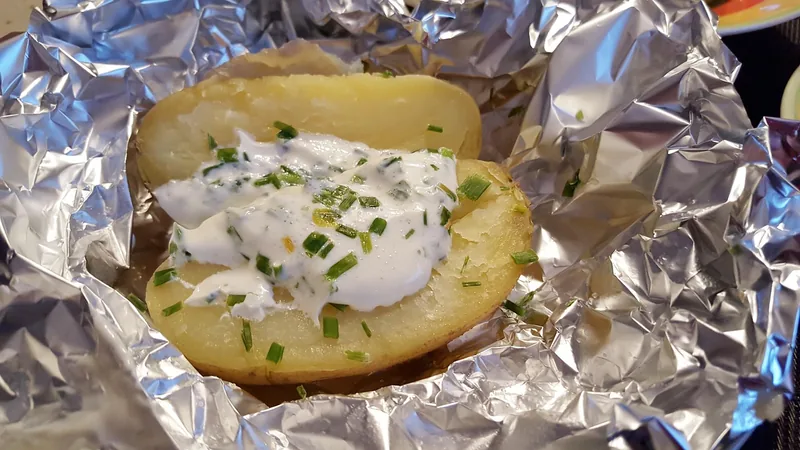 A potato baking in foil on the grill
