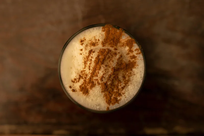 A glass of eggnog under a heavy dusting of cinnamon