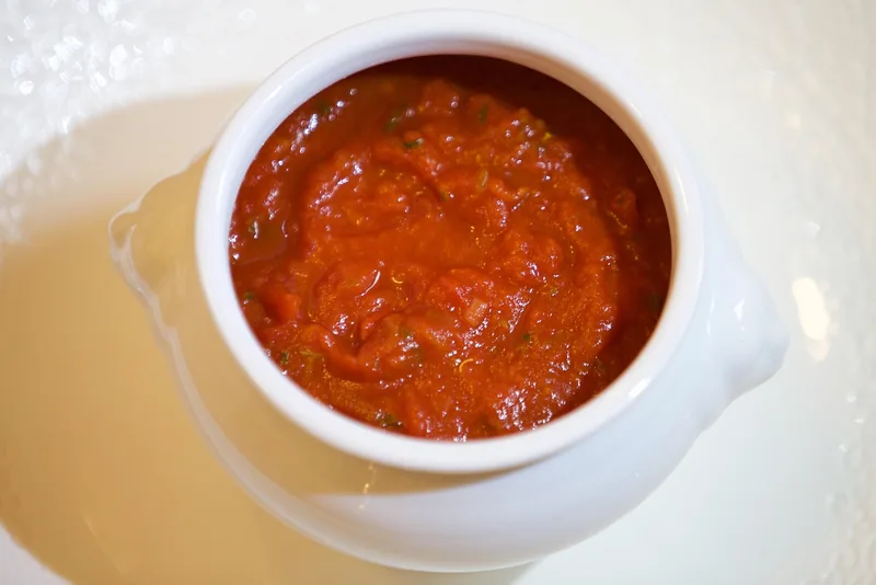 A white crock of red sauce