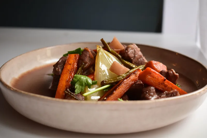 Beef stew with carrots and celery in a shallow bowl