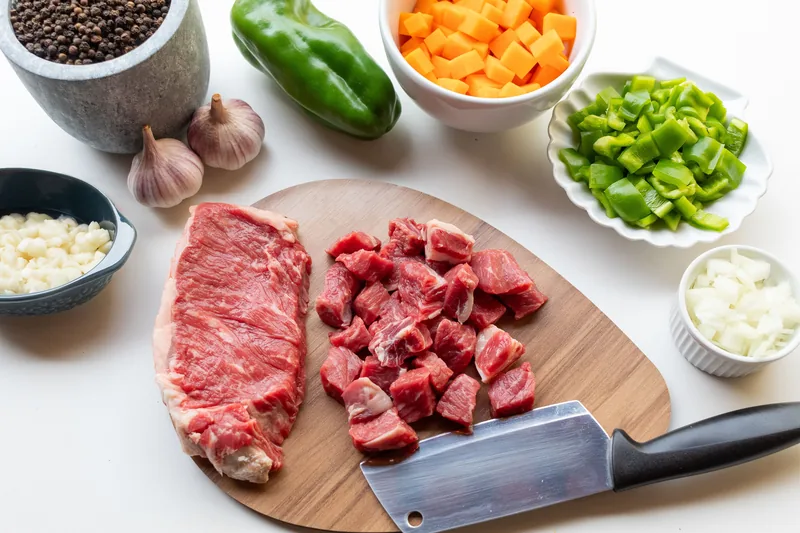 Diced beef and prepared vegetables on a board