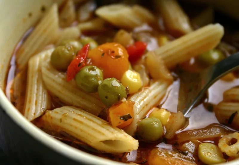 A bowl of tomato soup with pasta and vegetables