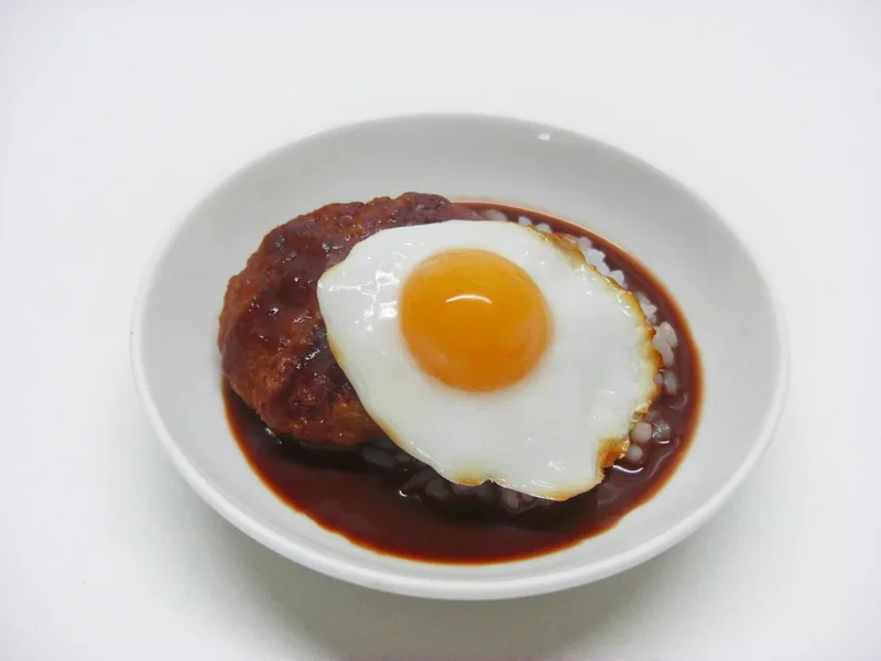 A hamburger patty topped with a fried egg in brown gravy