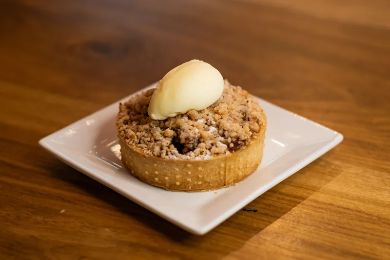 Apple crumble with a crisp baked topping and a scoop of vanilla ice cream