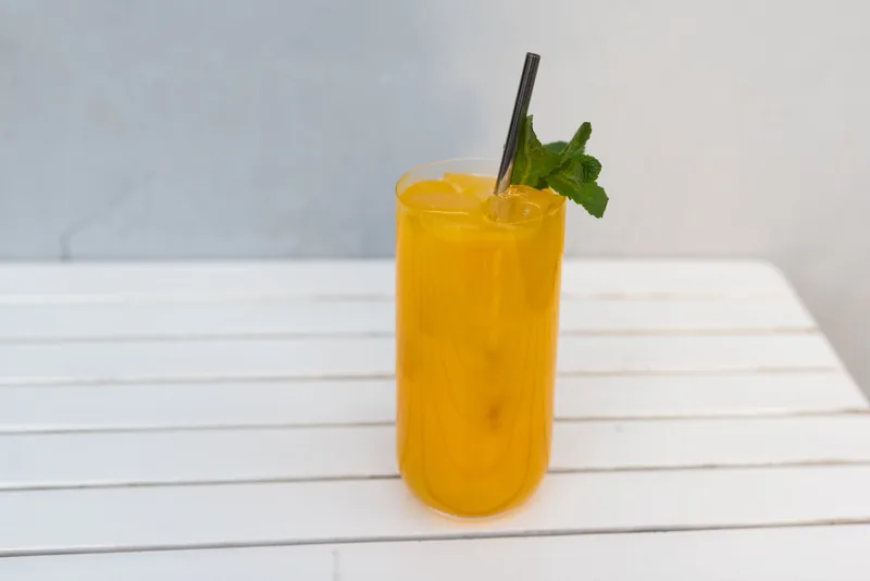 A tall glass of peach lemonade with mint
