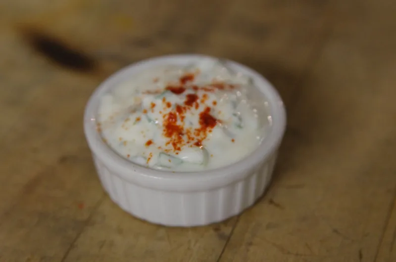 A ramekin of yogurt sauce dusted with paprika